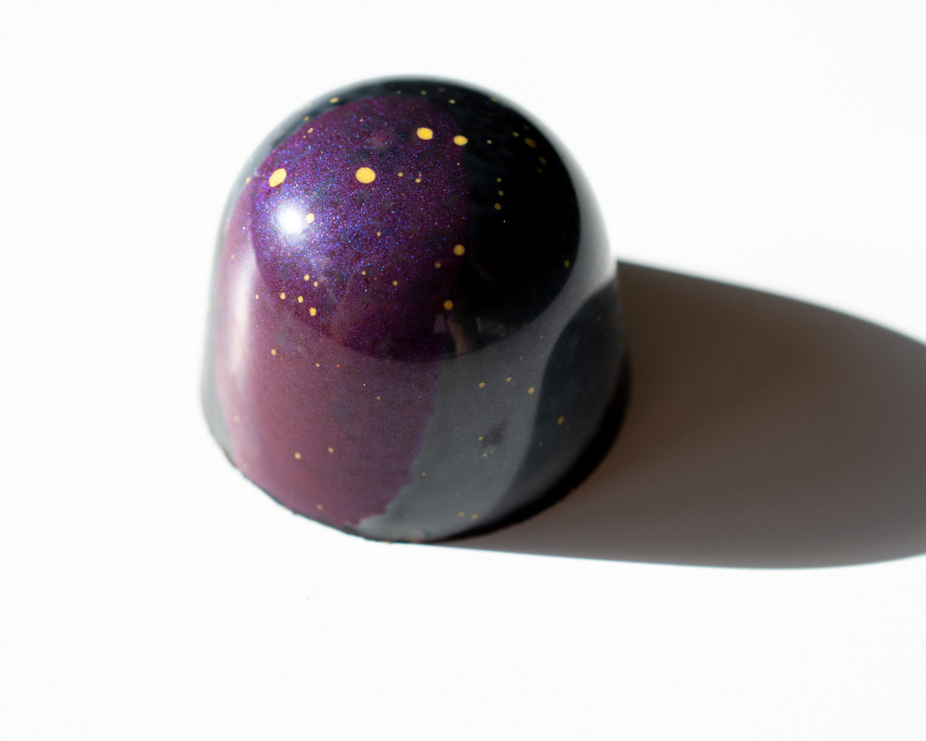 A single handcrafted Irish chocolate bonbon with gold speckles, a luxury treat or corporate client gift.