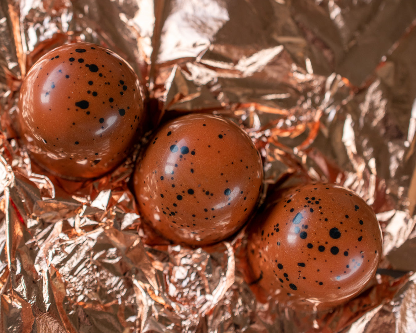 Speckled artisan Irish chocolate bonbons on copper foil, a handmade confectionery gifting idea for birthdays.
